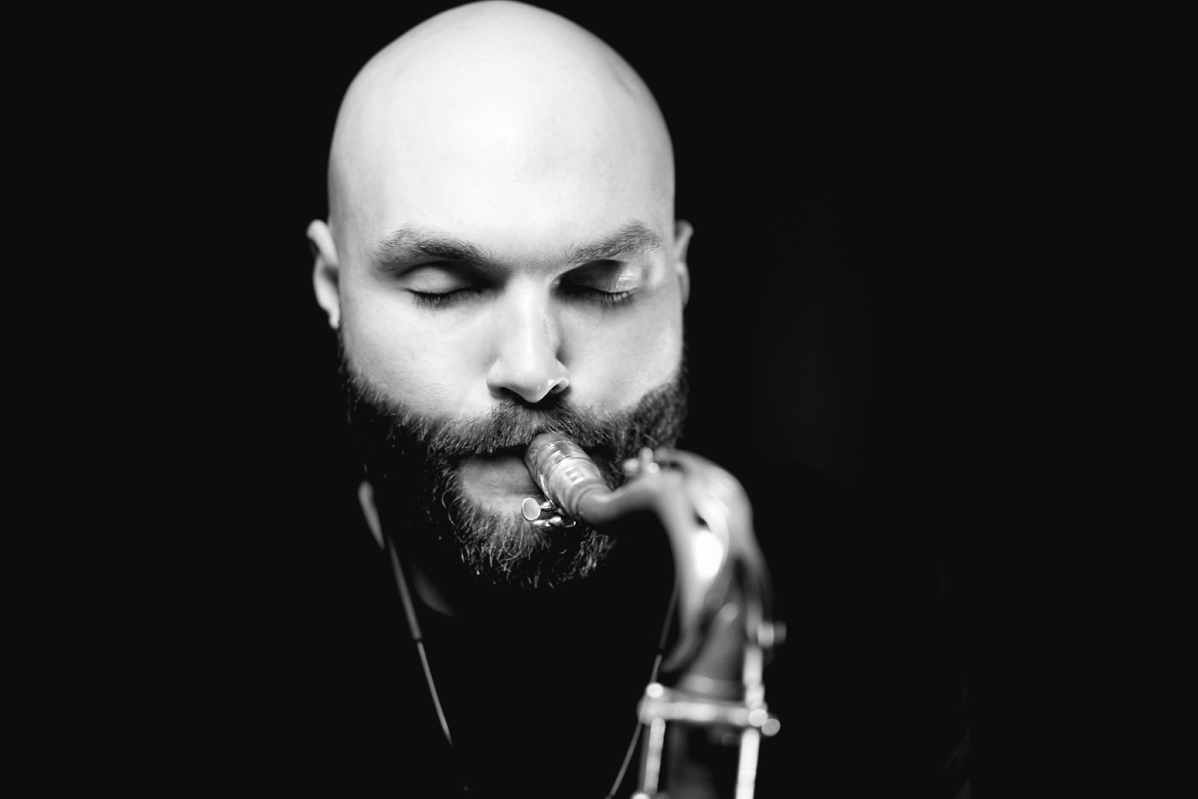 Black-and-white portrait of a saxophonist playing with his eyes closed