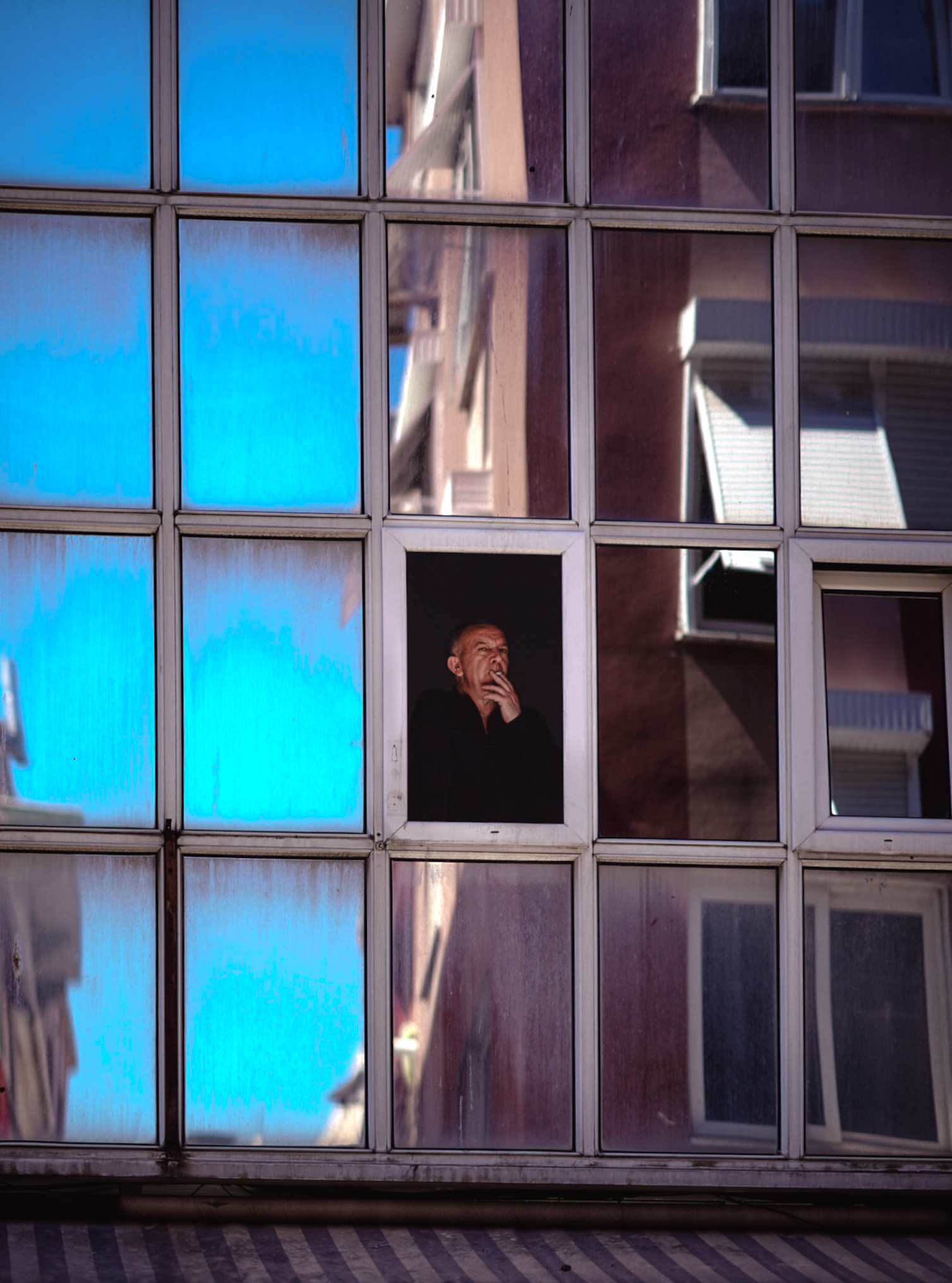 Man framed by geometric windows and reflections