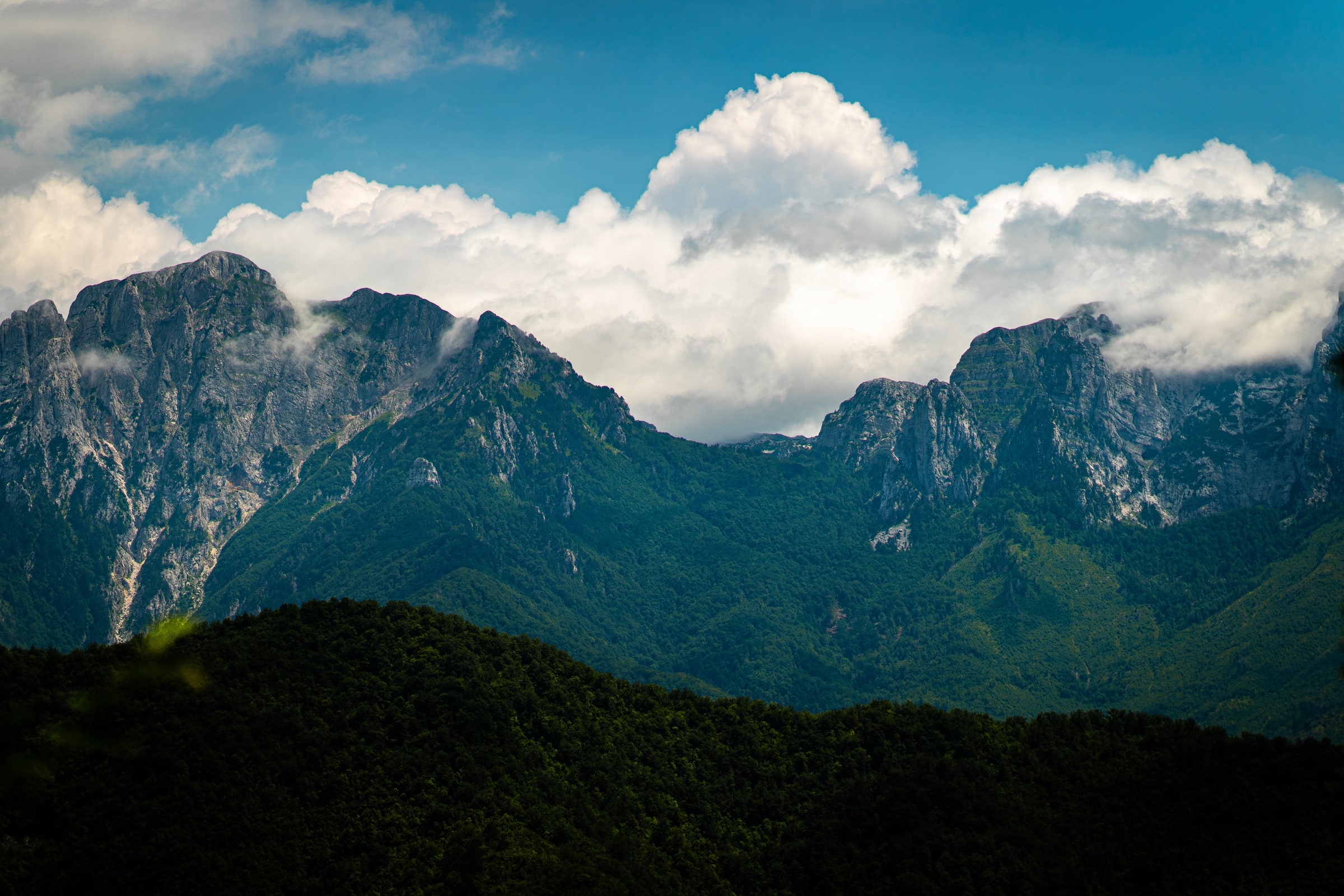 Mountain ridge rising into bright summer clouds