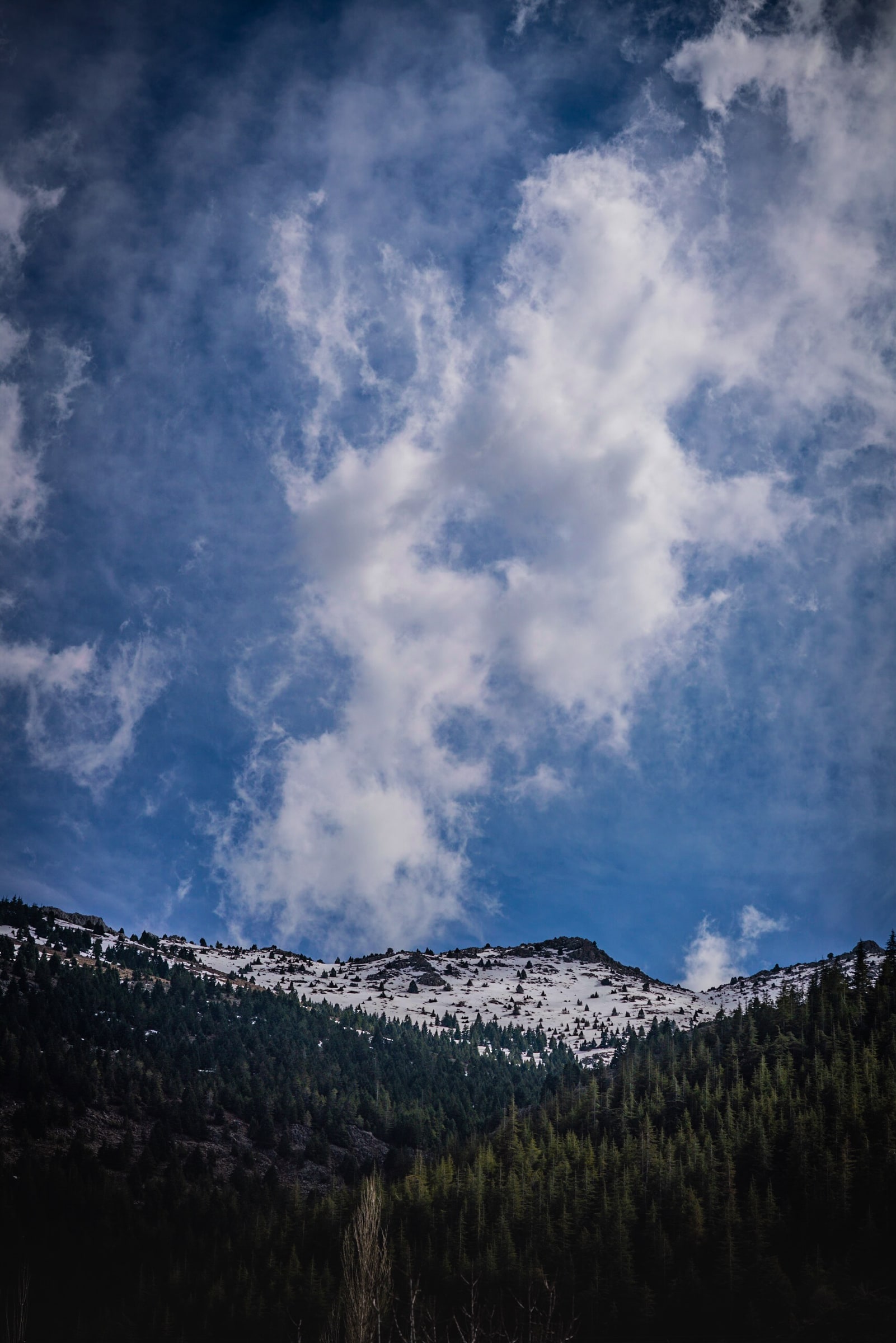 Snow-covered mountain below a vertical sweep of cloud