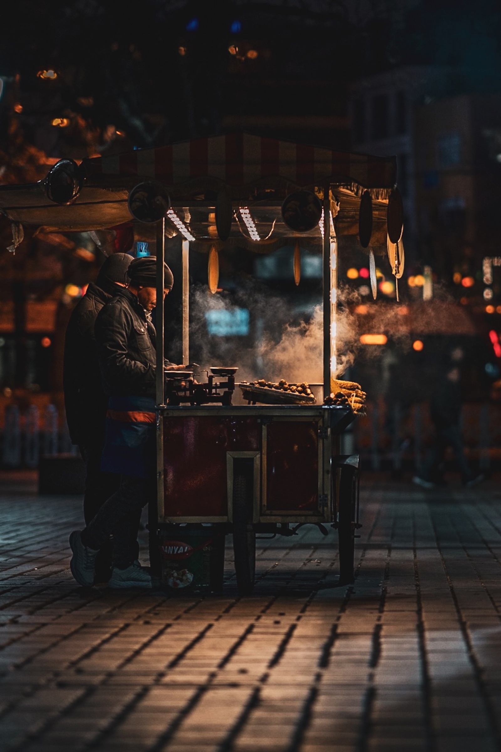 Street-food vendor working at a steaming cart at night