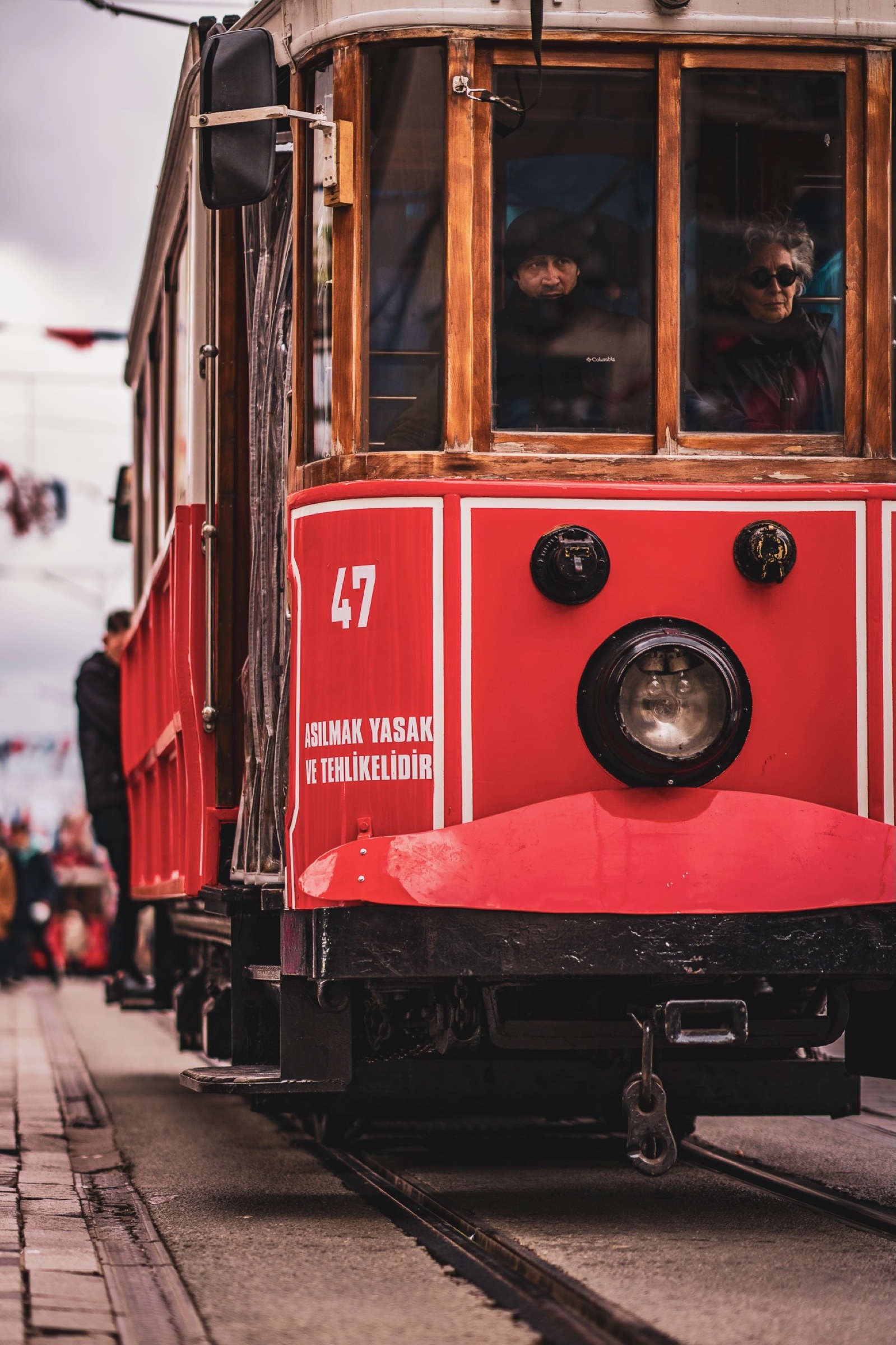 Red heritage tram number 47 with passengers behind its wooden windows